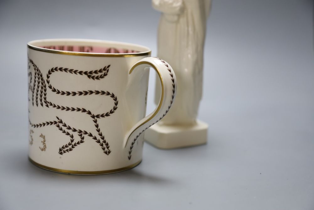 A Wedgwood commemorative Coronation mug designed by Richard Guyatt and an earthenware figure of a grape-carrier, indistinct signature b